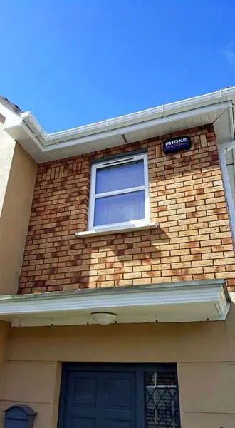 Water-fed pole cleaning the upstairs window of a brick-fronted house