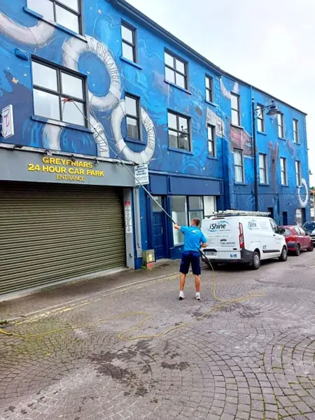Terry, iShine’s owner/operator, cleaning the windows of a city-centre building, with the iShine van parked outside