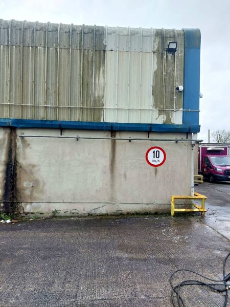 Warehouse cladding half cleaned, showing the clean and dirty sections side by side