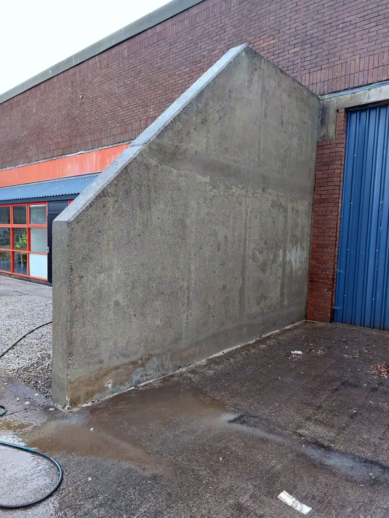 The same concrete wall clean after pressure washing