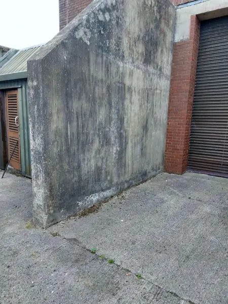 Concrete wall stained with dirt and algae before pressure washing