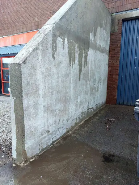 A concrete wall at a commercial unit halfway through pressure washing