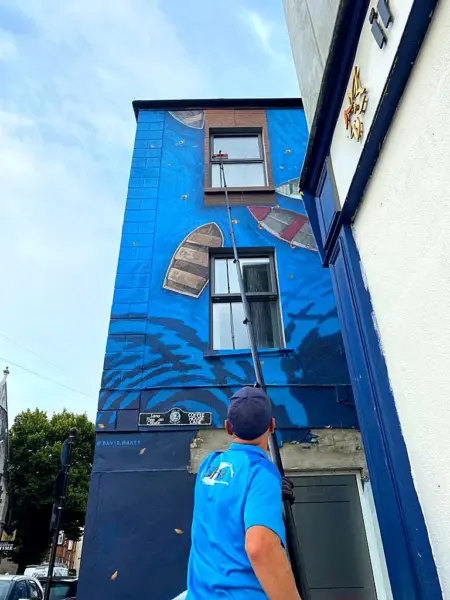 Terry, iShine’s owner/operator, cleaning the upper windows of a mural-painted building