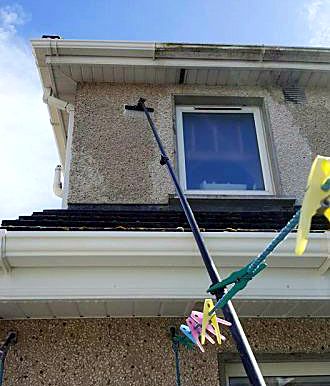 Water-fed pole cleaning an upstairs window on a pebbledash house