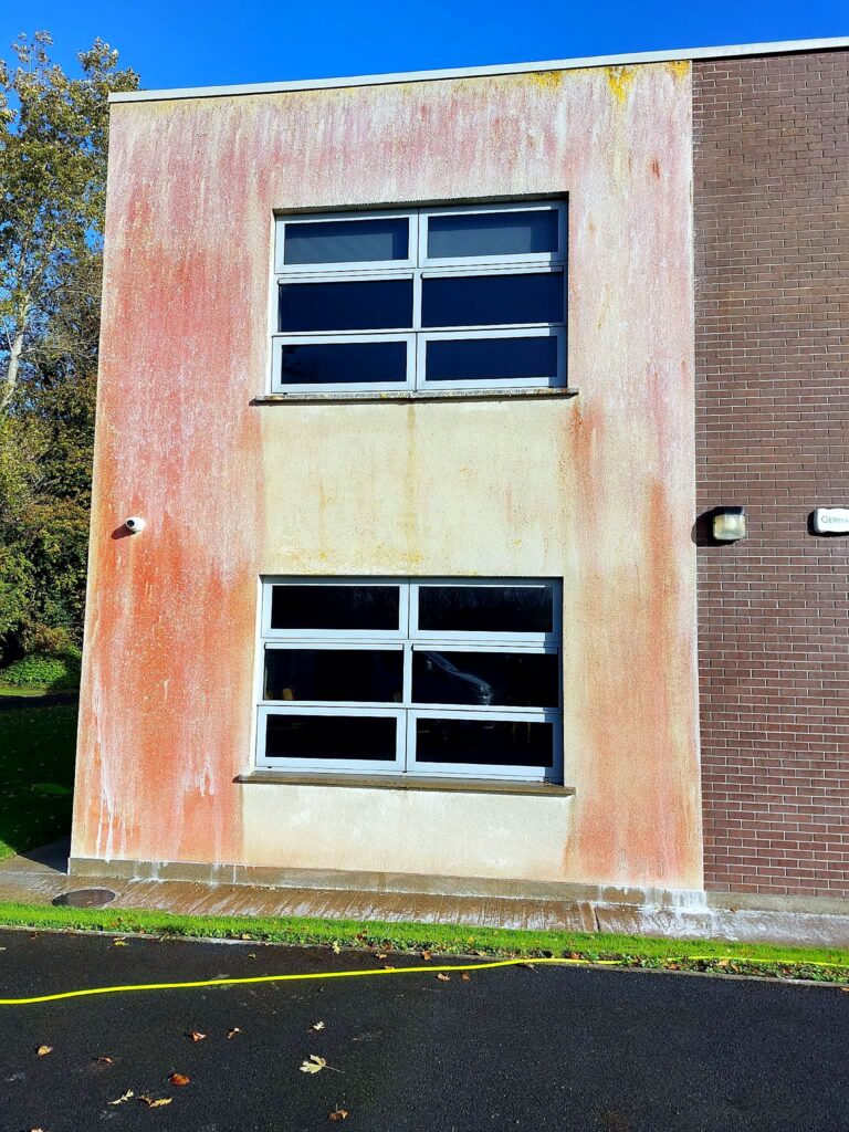 Red algae streaks running down the render of a two-storey commercial building