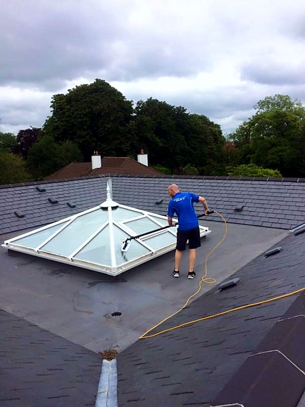 Terry, iShine’s owner/operator, cleaning a glass roof lantern on a flat roof