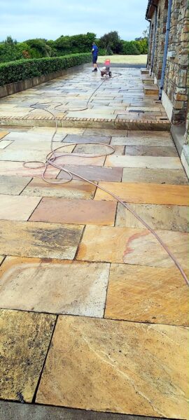 A sandstone patio being pressure washed