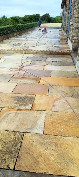 A sandstone patio being pressure washed
