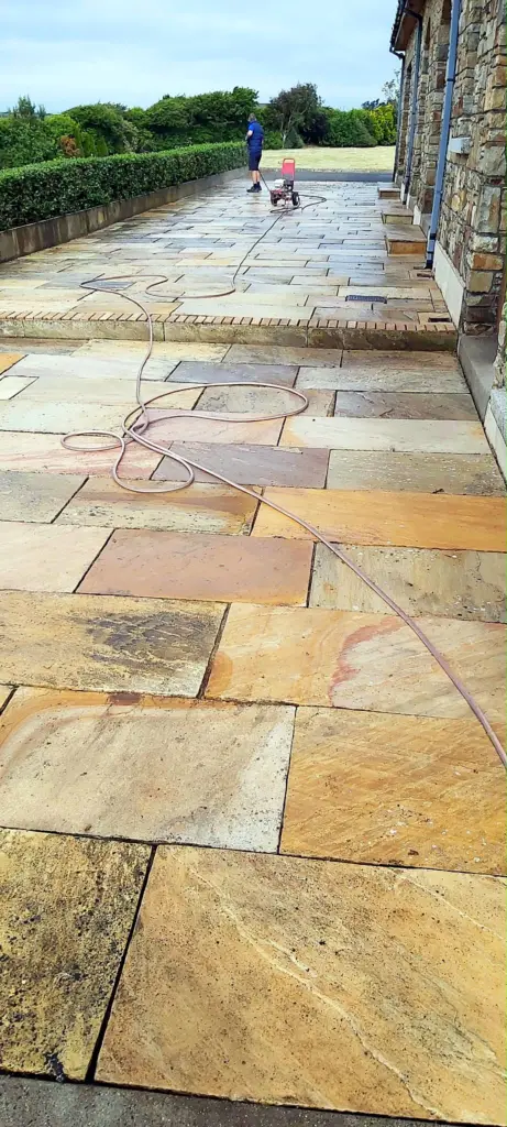 A sandstone patio being pressure washed