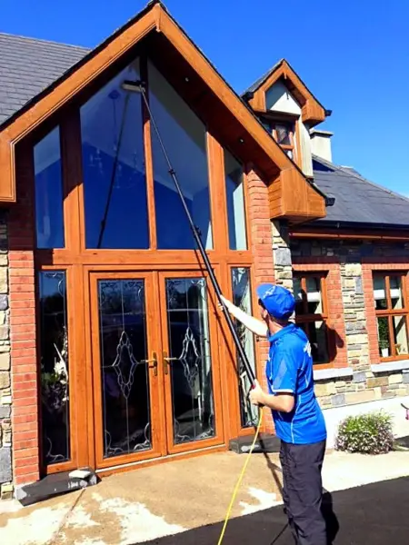 Terry, iShine’s owner/operator, cleaning a tall gable window on a timber-framed house