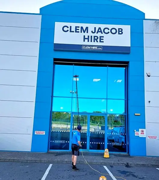 Cleaning the tall glass front of a hire company warehouse